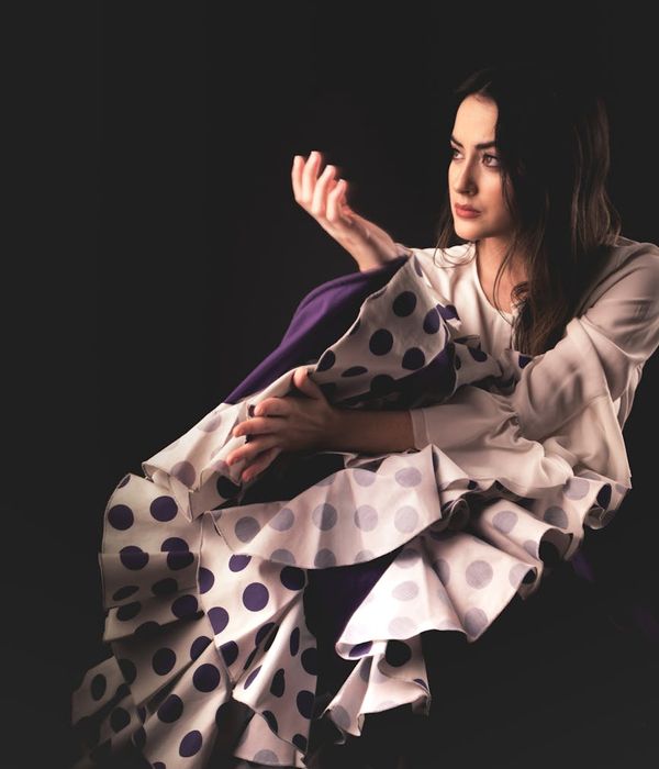 Woman in a flowing yoga pose against a dark background with amber light.